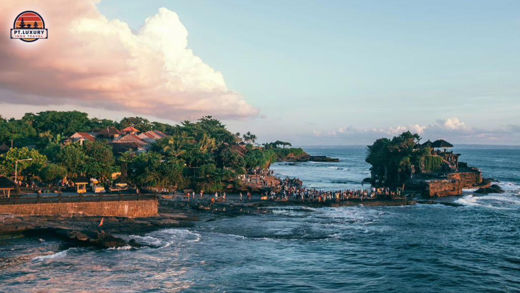Scenic view of Tanah Lot Temple in Bali with ocean waves, coastal landscape, and sunset sky.