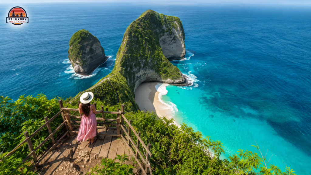 Spectacular aerial view of Kelingking Beach in Nusa Penida featuring dramatic limestone cliffs, turquoise ocean, and a scenic cliffside viewpoint.